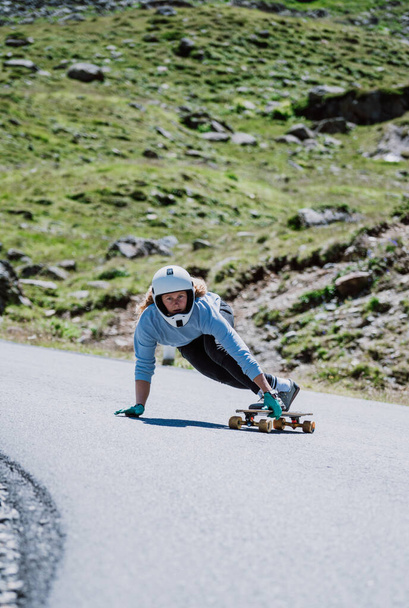 Filmreife Downhill-Longboard-Session. Junge Frau skateboardet und macht Tricks zwischen den Kurven auf einem Bergpass. Konzept über Extremsport und Menschen - Foto, Bild