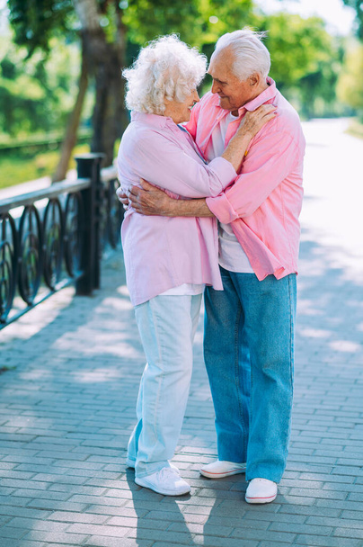 Old modern couple dressing fashionable colored clothes. Youthful grandmother and grandfather having fun outdoor and going wild. Representation of elderly people feeling young inside - Foto, Imagen