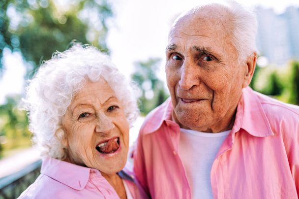 昔ながらのモダンなカップルはファッショナブルな色の服。若い祖母と祖父は屋外で楽しく野生になっています。中で若い感じの高齢者の表現 - 写真・画像