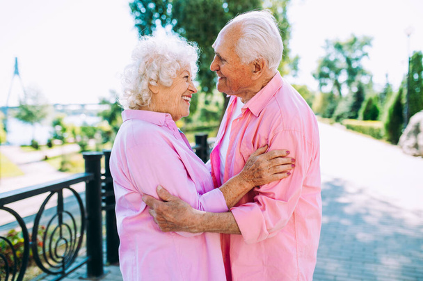 Old modern couple dressing fashionable colored clothes. Youthful grandmother and grandfather having fun outdoor and going wild. Representation of elderly people feeling young inside - Foto, Imagem