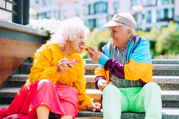 Old modern couple dressing fashionable colored clothes. Youthful grandmother and grandfather having fun outdoor and going wild. Representation of elderly people feeling young inside - Fotoğraf, Görsel