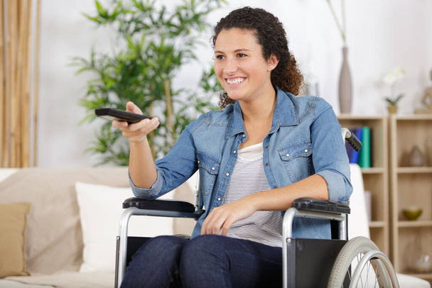 handicapped woman pressing tv remote - Foto, Bild