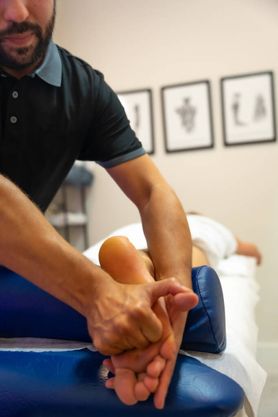 Physiotherapist in a physiotherapeutic massage to the client the sole of the foot, sports recovery - Foto, Bild
