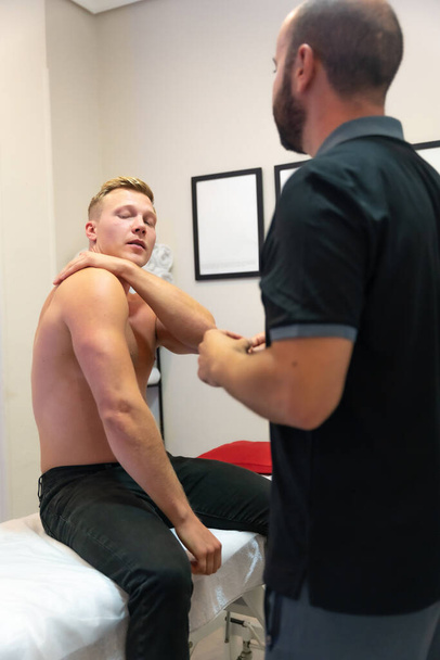 Client talk explaining shoulder pain to physiotherapist and sports osteopath - Foto, Imagem