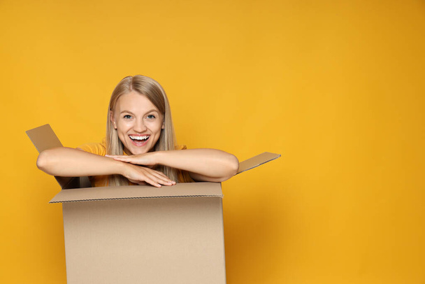 Концепція доставки і подарунка, молода жінка в коробці на жовтому тлі
 - Фото, зображення