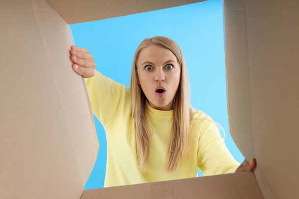 Concepto de entrega, regalo, sorpresa, mujer joven mirar en la caja de cartón - Foto, imagen