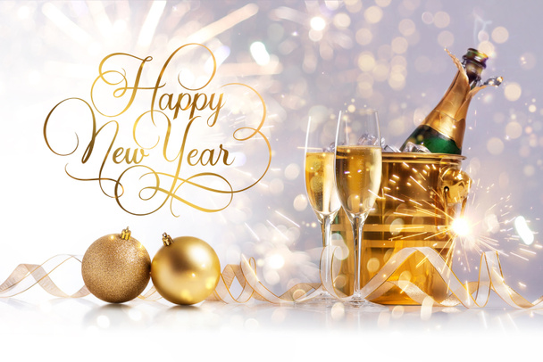 Boldog új évet! Két pohár pezsgő és egy üveg pezsgő egy arany vödörben, jéggel a bokeh és a csillagszórók hátterében. - Fotó, kép