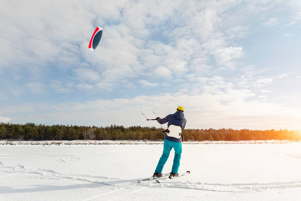 Vue panoramique de beaucoup de gens amis aiment monter kite surf board en costume chaud sur une journée d'hiver ensoleillée brillante à la surface enneigée de champ de lac gelé. Sport d'hiver adrénaline fun aventure passe-temps acitivité. - Photo, image