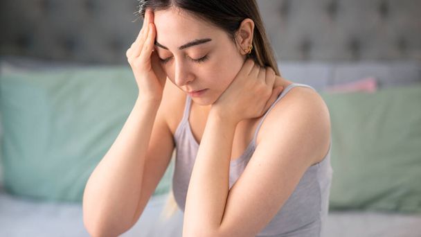 Surullinen väsynyt nuori nainen koskettaa otsaa, jolla on päänsärky migreeni tai masennus - Valokuva, kuva