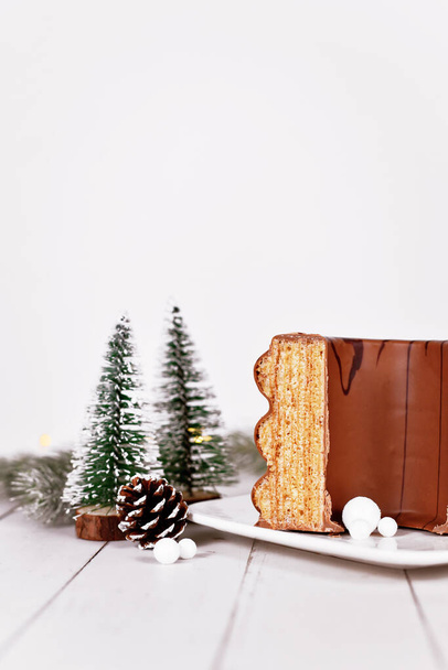Traditional German layered winter cake called 'Baumkuchen' glazed with chocolate, surrounded by seasonal decoration - Foto, Imagen