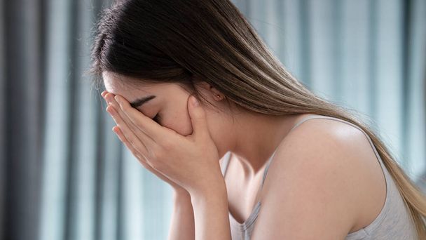 Λυπημένη κουρασμένη νεαρή γυναίκα που αγγίζει το μέτωπο με πονοκέφαλο ημικρανία ή κατάθλιψη - Φωτογραφία, εικόνα