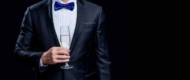 cropped view of tuxedo man cheering in studio. tuxedo man cheering with champagne. photo of cheering tuxedo man. tuxedo man cheering isolated on black background. - Foto, immagini