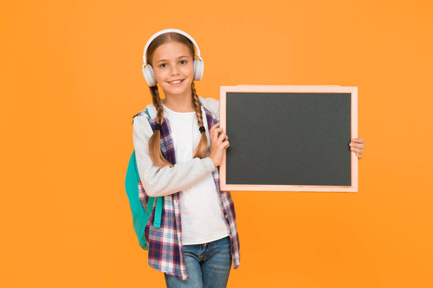 Look here. Cheerful girl hold blackboard. Back to school concept. Modern school life. Schoolgirl pupil informing you. School girl hold blank chalkboard copy space. Announcement and promotion. - Fotó, kép
