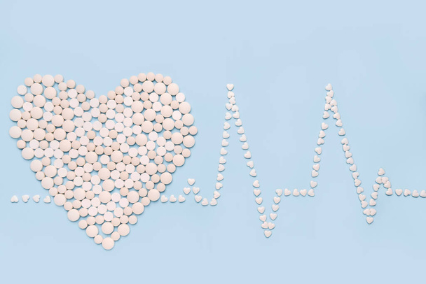 Pills in shape of the heart and heart rhythms. ECG. Medicine, healthcare and pharmacy concept  - Photo, Image