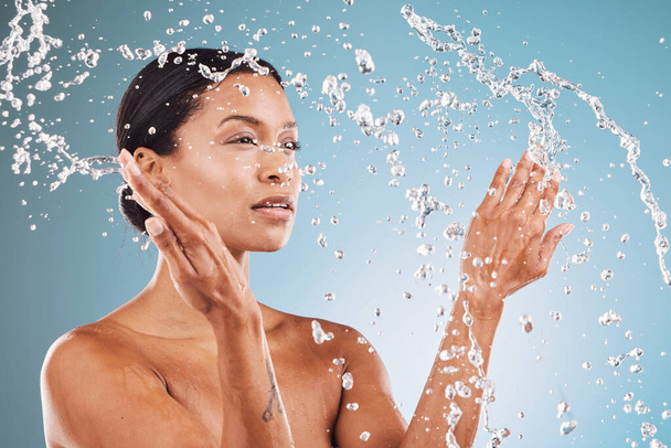 Beauty, skincare and black woman with splash of water for cleaning, hygiene and body care routine. Self care, wellness and healthy skin of model thinking with water splash in blue studio - Foto, immagini