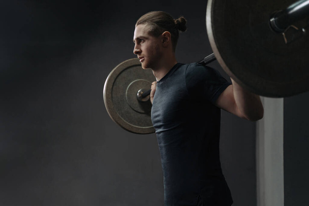 Porträt eines kaukasischen Athleten, der mit Barbel im Crossfit-Fitnessstudio trainiert. Funktionelles Zirkeltraining mit Crossfit-Geräten. Kopierraum - Foto, Bild