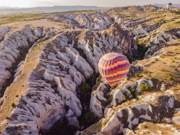 Colorful hot air balloons flying over at fairy chimneys valley in Nevsehir, Goreme, Cappadocia Turkey. Spectacular panoramic drone view of the underground city and ballooning tourism. High quality. - Foto, immagini