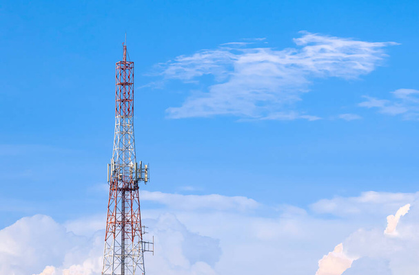Велика телекомунікаційна вежа з антеною проти білих хмар на фоні блакитного неба
 - Фото, зображення