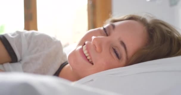 Bedroom, wake up and portrait of happy woman, shy and peekaboo with blanket, good morning and relax on comfortable pillow in Russia. Young girl waking up in bed after sleeping, healthy rest and nap. - Footage, Video