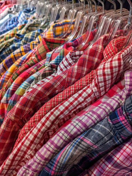 Many checkered shirts hang on hangers in a shop - Photo, Image