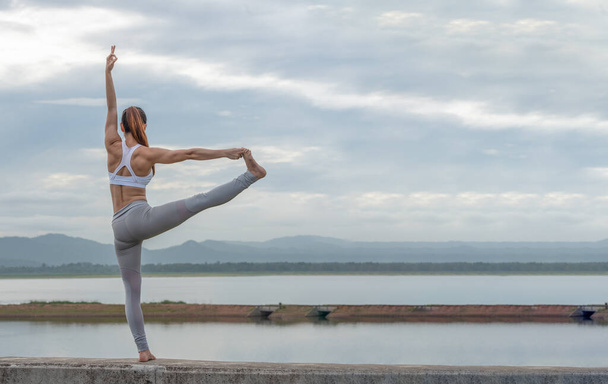 Jovem mulher asiática fazendo exercício de Yoga em belo lago com fundo de montanha na parte da manhã. - Foto, Imagem