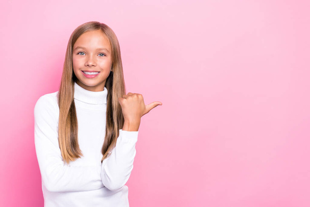 Photo of positive satisfied girl toothy smile white trendy sweater arm direct demonstrate empty space isolated on pink color background. - 写真・画像