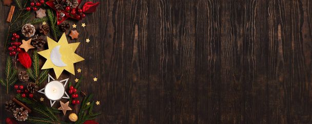 Χειμερινό ηλιοστάσιο, 21 Δεκεμβρίου. Η μεγαλύτερη βραδιά της χρονιάς. Ήλιος και φεγγάρι σύμβολο, χριστουγεννιάτικα δέντρα, κουκουνάρια, κλαδιά paddub με κόκκινα μούρα, κερί σε σκούρο ξύλινο φόντο, κορυφαία άποψη. - Φωτογραφία, εικόνα