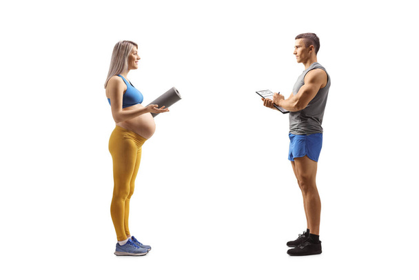 Pregnant woman in sportswear talking to a fitness coach isolated on white background - Φωτογραφία, εικόνα
