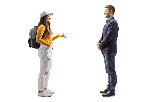 Full length profile shot of a female student with a backpack  talking to a man isolated on white background - Photo, image