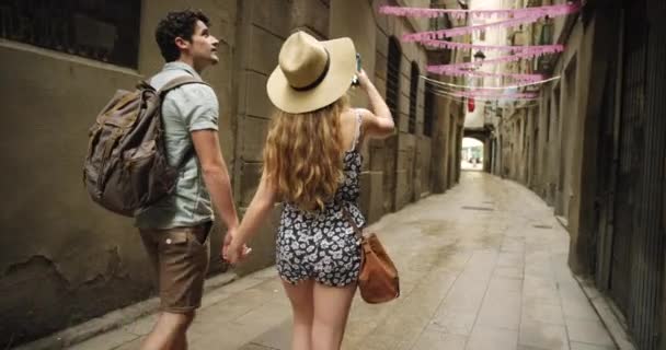 Travel couple and walking with phone selfie for adventure, journey and summer holiday together. Freedom, technology and vacation photograph memory of people on alley walk in Barcelona, Spain - Footage, Video