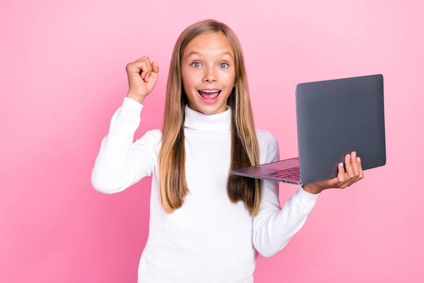Portrait of delighted excited girl raise fist celebrate hold netbook isolated on pink color background. - Φωτογραφία, εικόνα