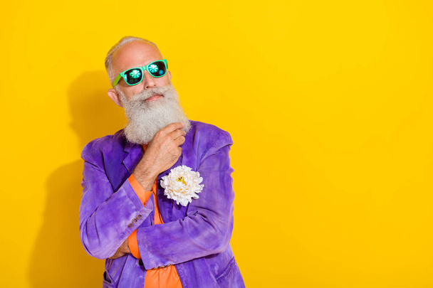 Portrait of minded serious aged person hand touch beard contemplate empty space isolated on yellow color background. - Foto, imagen