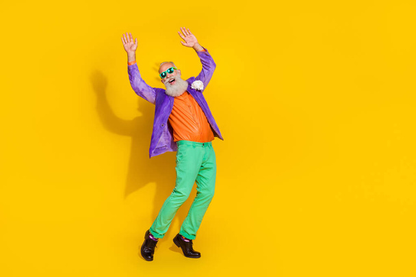 Full length photo of excited cool guy dressed violet velvet jacket rising hands enjoying disco isolated yellow color background. - Fotografie, Obrázek