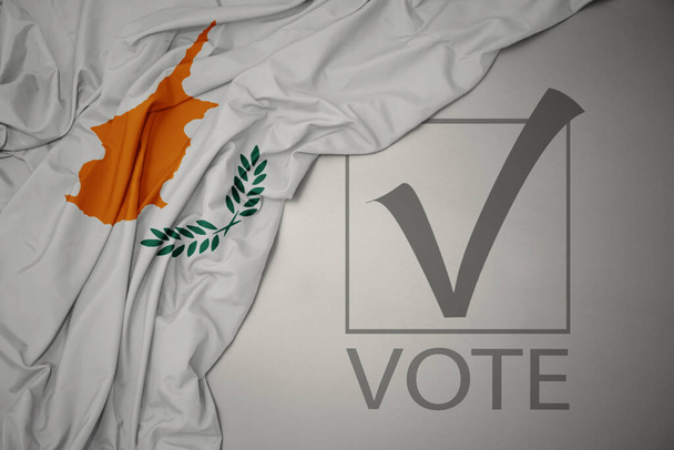 ondeando colorida bandera nacional de cyprus sobre un fondo gris con voto de texto. concepto de elección. Ilustración 3D - Foto, imagen