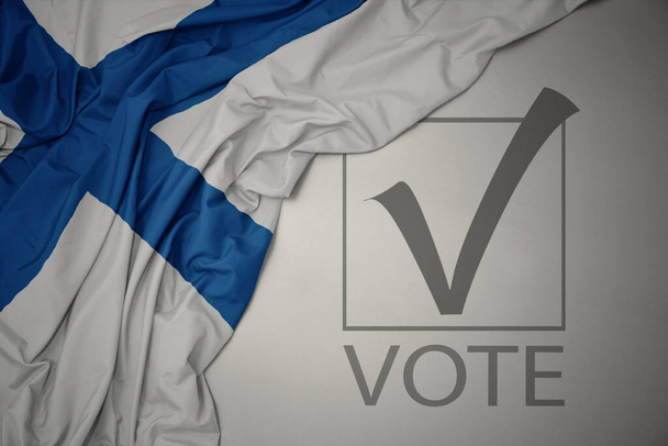 heiluttaen värikästä Suomen lippua harmaalla taustalla tekstiäänestyksellä. Vaalikonsepti. 3D-kuva - Valokuva, kuva