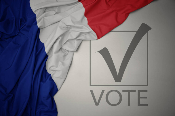 ondeando colorida bandera nacional de Francia sobre un fondo gris con voto de texto. concepto de elección. Ilustración 3D - Foto, imagen