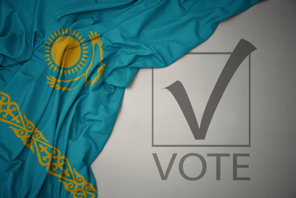 ondeando colorida bandera nacional de Kazajstán sobre un fondo gris con voto de texto. concepto de elección. Ilustración 3D - Foto, imagen