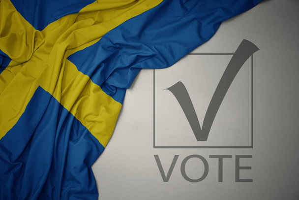 ondeando colorida bandera nacional de Suecia sobre un fondo gris con voto de texto. concepto de elección. Ilustración 3D - Foto, imagen