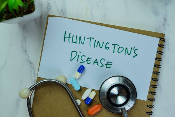 Έννοια της νόσου του Huntington γράφουν σε αυτοκόλλητες σημειώσεις που απομονώνονται στο ξύλινο τραπέζι. - Φωτογραφία, εικόνα