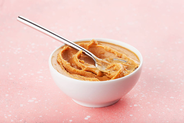 manteiga de amendoim lisa na tigela no fundo rosa - Foto, Imagem