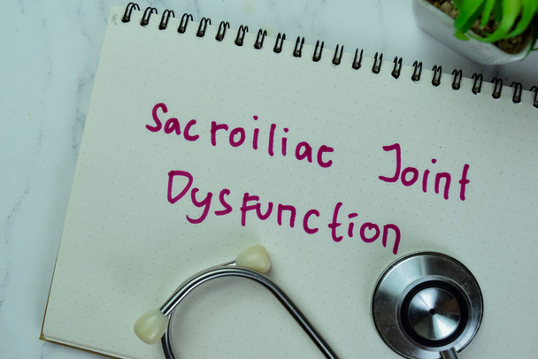 Concept of Sacroiliac Joint Dysfunction write on a book isolated on Wooden Table. - Photo, Image