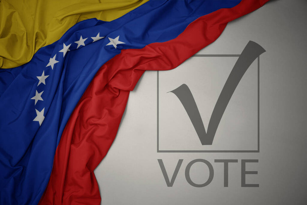ondeando colorida bandera nacional de venezuela sobre un fondo gris con voto de texto. concepto de elección. Ilustración 3D - Foto, imagen