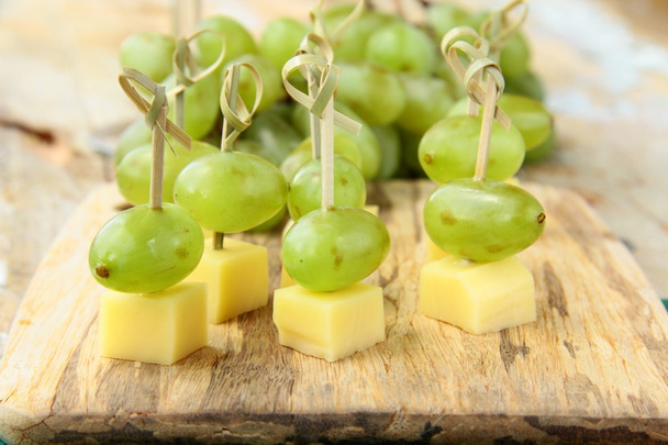 Aperitivo queso de canapé con uvas blancas en pinchos de bambú
 - Foto, Imagen