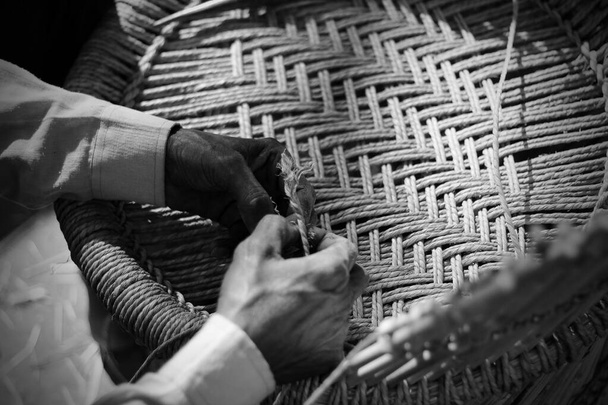 Artesano experto trabajando manualmente un sillón de madera de bambú detallado con sus dedos y herramientas - Foto, imagen