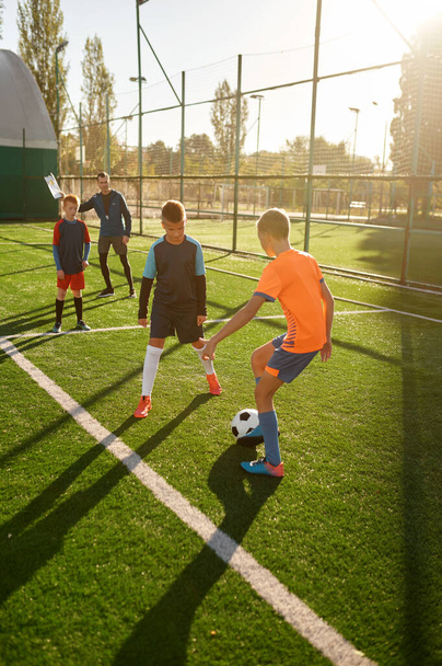 Νεαρά αγόρια που παίζουν ποδόσφαιρο στην κατασκήνωση για παιδιά. Αθλητικό τουρνουά για τη νεολαία την ημέρα του καλοκαιριού - Φωτογραφία, εικόνα