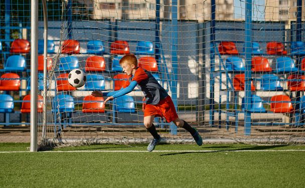 Junior portiere cattura palla mentre difende cancello nella partita di calcio. Allenamento della squadra di calcio o torneo di competizione - Foto, immagini