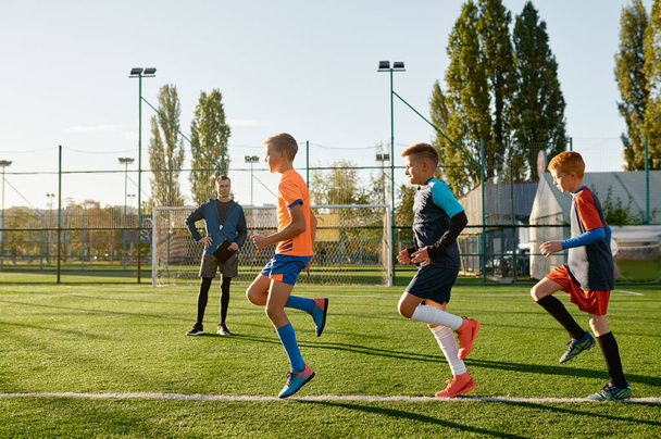 Kids practicing soccer on grass field under football coach control. Group of young boys exercising on stadium - Foto, Bild