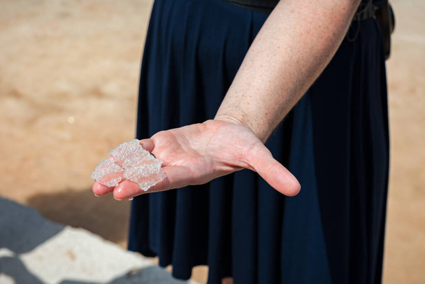 Flower of salt, is a salt that forms as a thin, delicate crust on the surface of seawater in the hand of a women, freshly collected from the salt field. Flower of sea salt crystals isolated on hand. - Zdjęcie, obraz