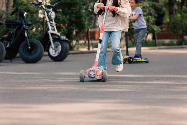 Little girl playing with a scooter in the cit - Φωτογραφία, εικόνα