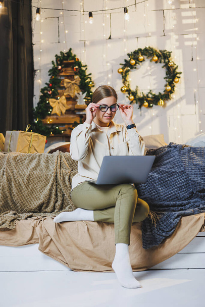 Belle femme de Noël Joyeux boire une tasse de chocolat chaud, porter des vêtements confortables à la maison, regarder l'ordinateur portable, travailler à distance pour la nouvelle année, carreaux, humeur d'hiver du Nouvel An. - Photo, image